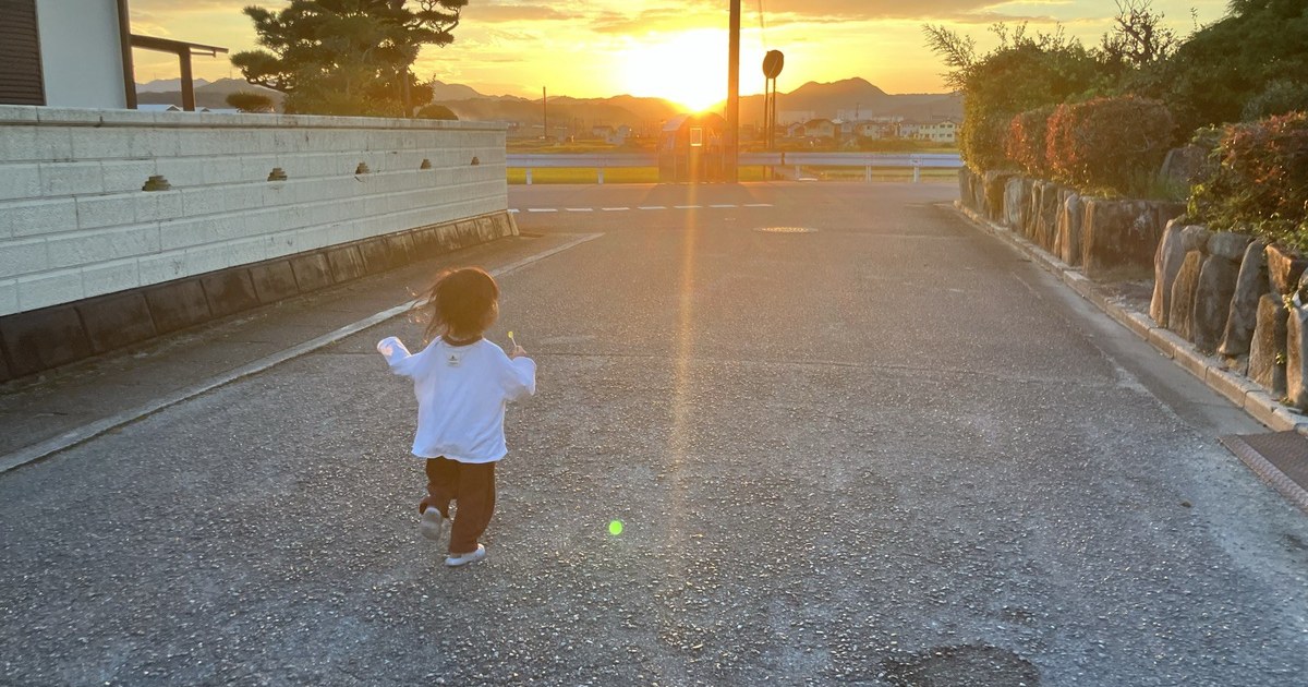 夕日の道を歩く娘